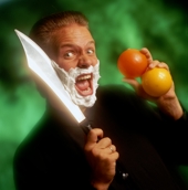 Paul Isaak about to shave his face with a huge knife while juggling it.